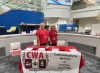 Two CWA members in red shirts stand behind a table with a CWA Local 6001 sign