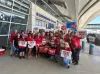 American Airlines passenger service workers in red shirts holding signs that read "Largest Airline Lowest Pay"